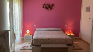 Un dormitorio con una pared rosa y una cama en B&B Casa Losea, en Castello delle Forme