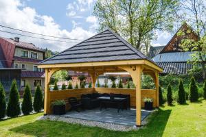 a wooden gazebo with a table and chairs in a yard at U Tatarów in Suche