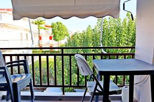 einen Tisch und zwei Stühle auf einem Balkon mit einem Tisch und einem Sonnenschirm in der Unterkunft Το Κοράλι in Amarinthos