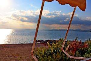 a beach with an umbrella and the ocean at Το Κοράλι in Amarinthos