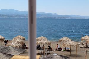 eine Gruppe von Menschen, die am Strand mit Sonnenschirmen sitzen in der Unterkunft Το Κοράλι in Amarinthos