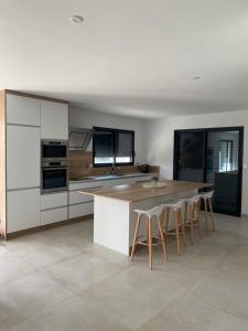 una cocina con armarios blancos, mesa y taburetes en Villa St Julien 10 mn de Dijon en Saint-Julien