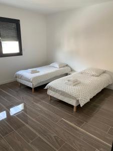 two beds in a room with wooden floors at Villa St Julien 10 mn de Dijon in Saint-Julien
