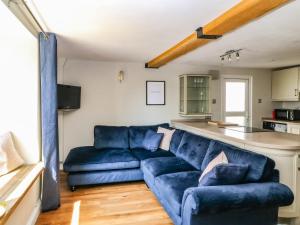 sala de estar con sofá azul y cocina en Old Town House en Dawlish