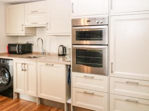 una cocina con armarios blancos y electrodomésticos de acero inoxidable en Old Town House en Dawlish