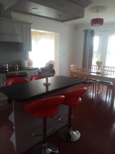 a kitchen with a black counter and red bar stools at Golf Beach 5 min walk away and we have wifi in Luddan +3 photos