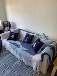 un sofá con almohadas azules en una habitación en Lovely well equipped apartment - 2 bedroom, sleeps 4, sundeck, 8 min river walk to beach and town, FREE parking permit ! en Lyme Regis
