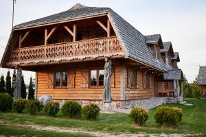 a large wooden house with a balcony on it at Siedlisko Sodyba in Puńsk