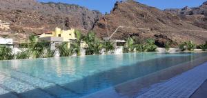 a swimming pool with blue water in the mountains at Alse Homes Adeje Plaza in Adeje