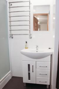 ein weißes Badezimmer mit einem Waschbecken und einem Spiegel in der Unterkunft Апартаменти для великої компанї в центрі міста in Lwiw