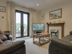 a living room with a couch and a tv and a fireplace at Columbine Cottage in Bude