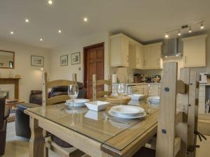 a kitchen and dining room with a wooden table with wine glasses at Columbine Cottage in Bude