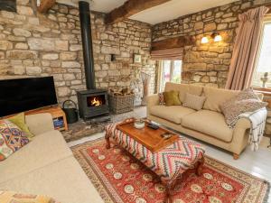 a living room with a couch and a fireplace at Litton Hall Barn Cottage in Skipton