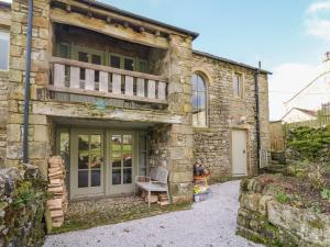 a stone house with a balcony on the side of it at Litton Hall Barn Cottage in Skipton