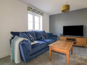 a living room with a blue couch and a tv at 4 Trerammet Crescent in Tintagel