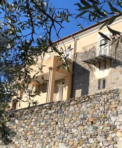 un edificio detrás de una pared de piedra con una valla en Agriturismo Le Merline en Arnasco