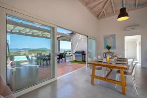 a dining room with a table and a view of the ocean at Alghero Villa Carrabufas villa con piscina vista mare per 10 persone in Valverde