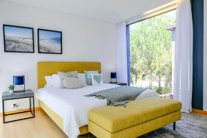 a bedroom with a large bed and a large window at Troia Atlantic Villas - Moradia Prime in Troia
