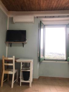 Cette chambre dispose d'une table, d'une télévision et d'une fenêtre. dans l'établissement Casa Vacanze Il Vicolo - Oliveto Citra, à Oliveto Citra