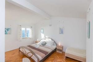 een witte slaapkamer met een bed en een raam bij Apartmani Neno in Lokva Rogoznica