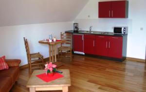 a living room with a table and a kitchen with red cabinets at Apartments Mester in Xanten