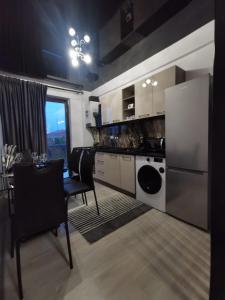 a kitchen with a refrigerator and a table with chairs at Lumandi LS residence in Mamaia Nord