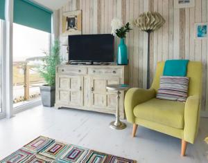 a living room with a yellow chair and a television at The View in Port Isaac