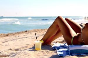 a woman in a bikini laying on the beach with a drink at Seacoast Suites on Miami Beach in Miami Beach