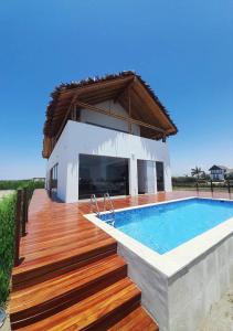 een huis met een zwembad en een houten terras bij CASA LUNA in Chincha Baja