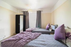 um quarto com 2 camas e almofadas roxas em Virexxa Aylesbury Centre - Executive Suite - 2Bed Flat with Free Parking em Aylesbury