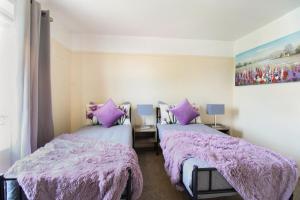 Duas camas num quarto com cobertores e almofadas roxos em Virexxa Aylesbury Centre - Executive Suite - 2Bed Flat with Free Parking em Aylesbury