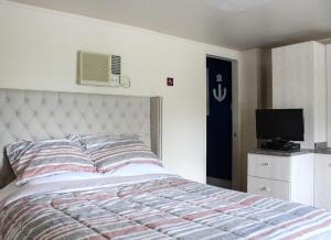 - une chambre avec un lit et une télévision à écran plat dans l'établissement Le Marigot, à Vaudreuil-Dorion