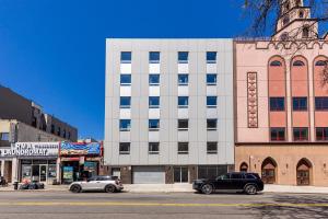 two cars parked in front of a building on a street at Astoria Inn LaGuardia Hotel in Steinway