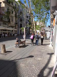 Un uomo seduto su una panchina in una strada di città di Neruda Chic House Vomero a Napoli