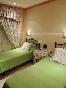 1 dormitorio con 2 camas verdes y 2 mesas en Fuengirola Apartamento vacacional MEDITERRANEO REAL, en Fuengirola