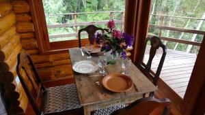uma mesa de madeira com um vaso de flores num alpendre em Eco Lodge Itororó em Nova Friburgo