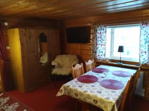 a dining room with a table with purple plates on it at Mysig stuga i Vasaloppsbyn Evertsberg in Älvdalen +1 photo