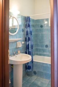 W wyłożonej niebieskimi kafelkami łazience znajduje się umywalka i wanna. w obiekcie Eleni's House Chorefto w mieście Zagora