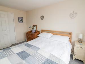 een slaapkamer met een wit bed en een houten hoofdeinde bij Merlin in Kingsbridge