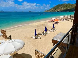 ein Strand mit Liegestühlen und Sonnenschirmen und das Meer in der Unterkunft GRAND VIEW Luxury water front studio at Grand Case in Grand Case