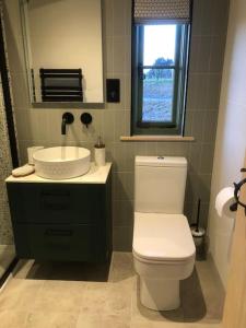 a bathroom with a white toilet and a sink at Coldharbour Luxury Shepherds Hut in Stone