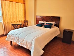 een slaapkamer met een groot wit bed met blauwe kussens bij Hostal Ukumari Andino in Cuzco