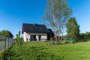 a white house with a black roof in a yard at Siedlisko pod brzozami in Sasino