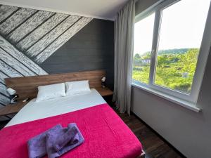 a bedroom with a bed with a red blanket and a window at Шале у моря in Tsandrypsh