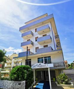 Un alto edificio bianco con un cartello davanti di Hotel Arabesco a Rimini