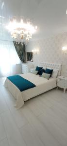 a white bedroom with a large bed and a chandelier at VIP Апартаменты СВЕТ ЕСТЬ ВСЕГДА!!! in Dnipro +17 photos