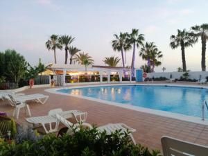 a swimming pool with chairs and palm trees at Blue Wave in San Miguel de Abona