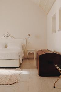 a white bedroom with a bed and a table at Masseria Petrusella in Giuggianello