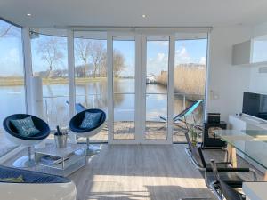 a living room with chairs and a view of the water at Homeboat Glamping in Nieuwpoort