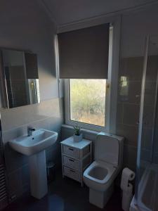 ein Bad mit einem Waschbecken, einem WC und einem Fenster in der Unterkunft Traeth Teras (Beach Terrace) in Llandudno